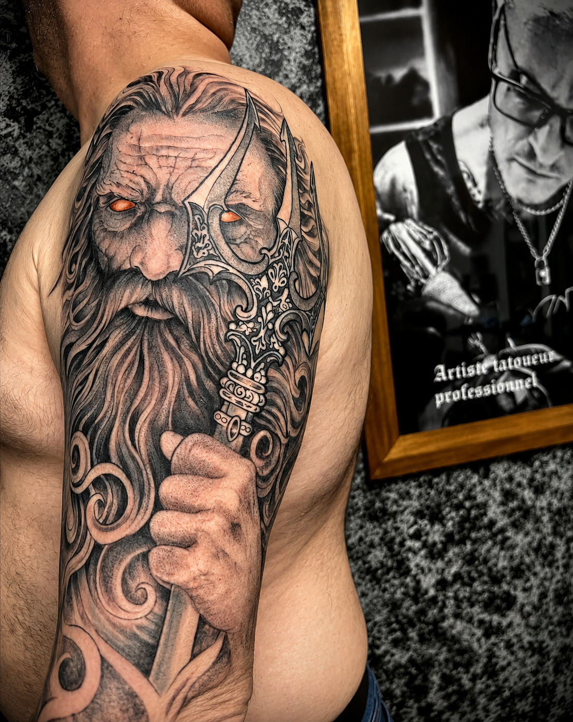 Tatouage réaliste noir et gris inspiré de la mythologie nordique représentant Odin avec Gungnir et un œil lumineux, réalisé en manche sur le bras chez KavaDerma à Drummondville.