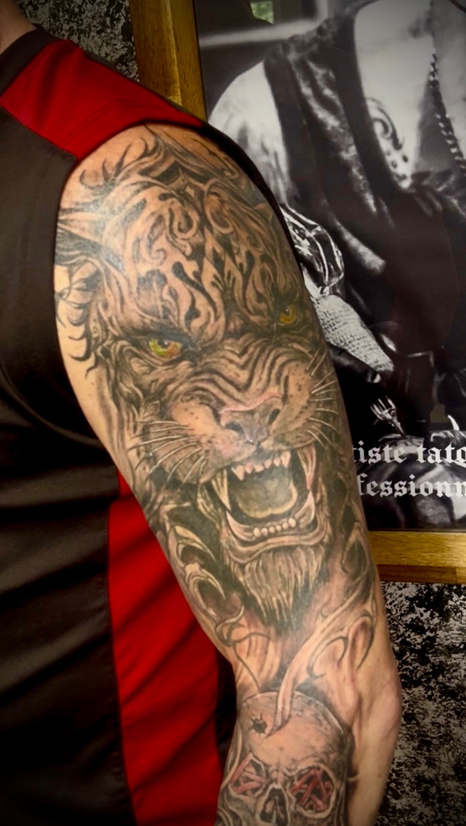 Tatouage réaliste noir et gris d'un tigre rugissant avec motifs tribaux et yeux verts sur le bras, réalisé chez KavaDerma à Drummondville.